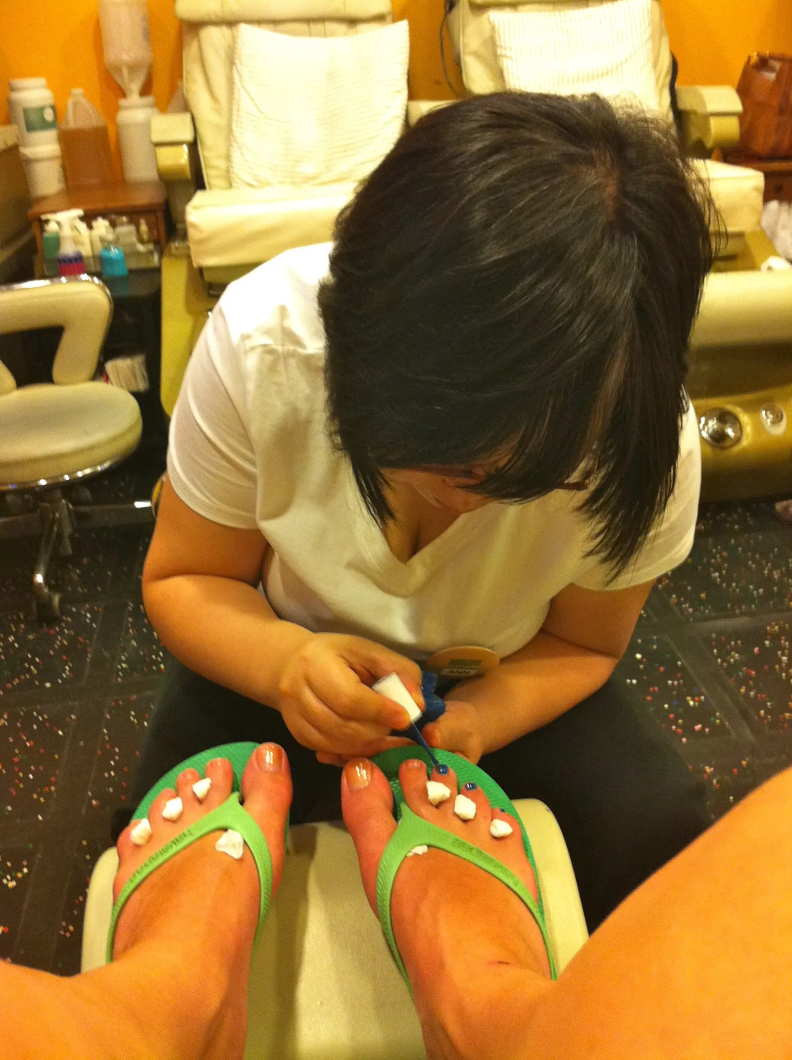 A nail tech painting toenails during a pedicure